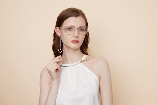 A stylish woman poses elegantly in fashionable eyeglasses and minimal white attire.