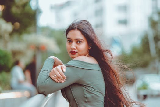 Woman with long hair posing outdoors, wearing green top.