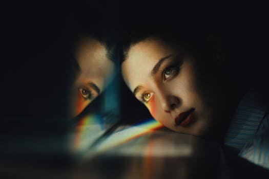 Artistic portrait of a woman reflecting in a mirror with rainbow hues.