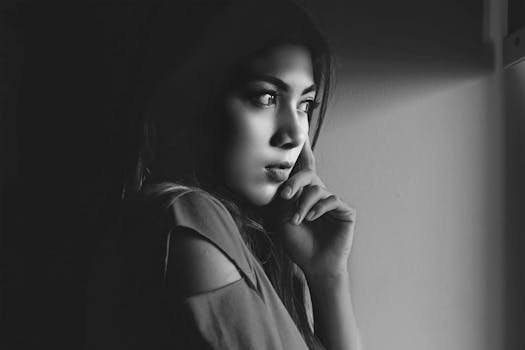 A thoughtful woman gazes out, captured in a dramatic black and white portrait.