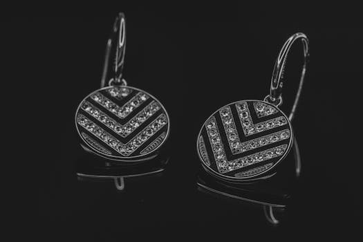 Pair of silver earrings with diamond-like crystals on black background.